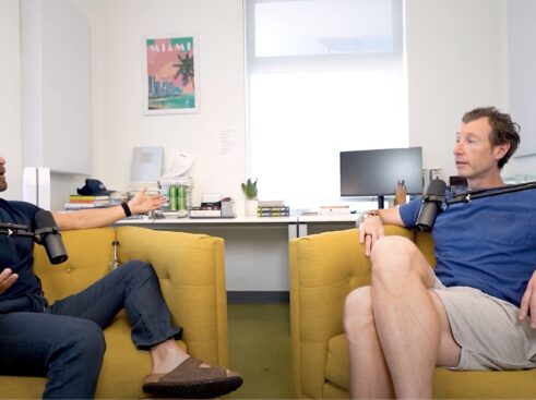 jason and greg sitting in yellow chairs behind podcast microphones