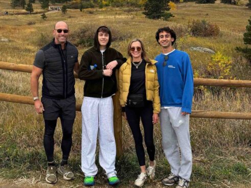 greg scheinman and family standing and smiling in front of a fence